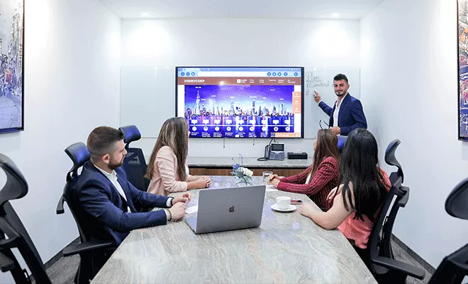 Boardroom at Qubic Square with people meeting and presenting using high-tech, fully equipped facilities.