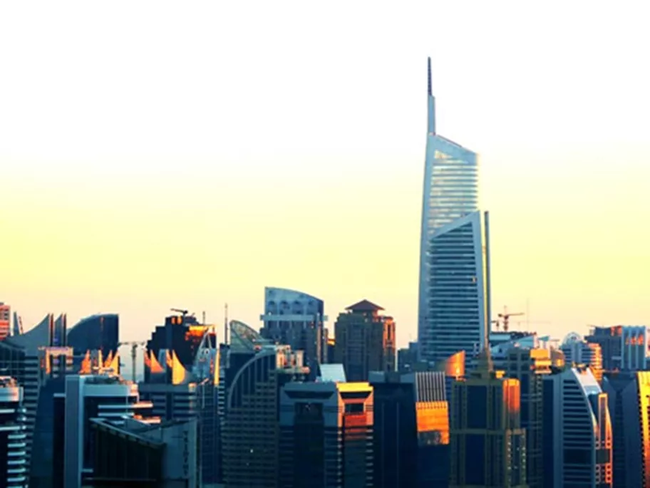 Tall modern skyscrapers at sunset, with Almas Tower standing prominently above the city skyline.